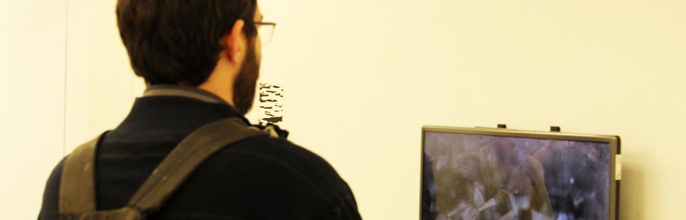מבקר בתערוכה "כתמים שחורים" צופה במיצג וידאו